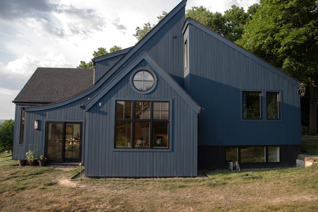 A Blue House Featuring a Prominent Large Window and an Equally Large Door