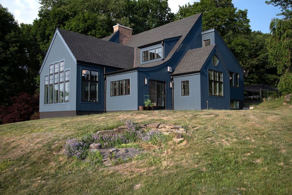 A Blue House Stands Prominently in Front of a Large Grassy Hill