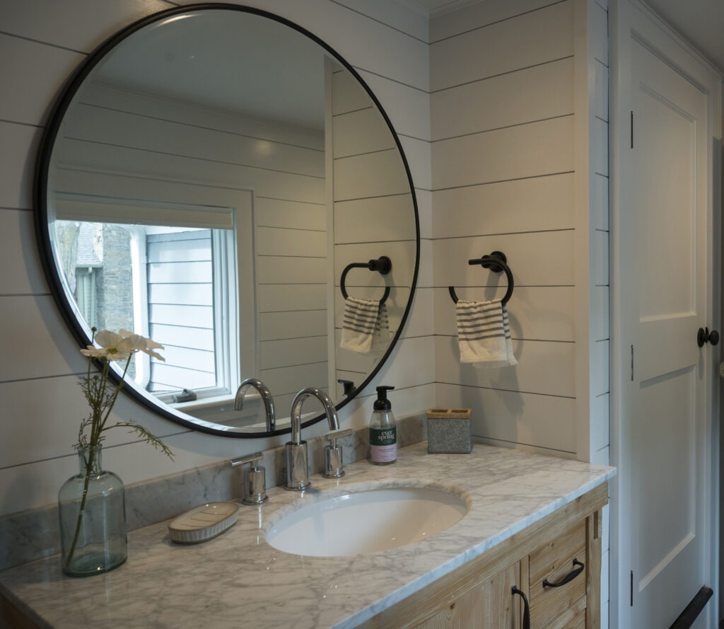 bathroom sink area with a large circular mirror